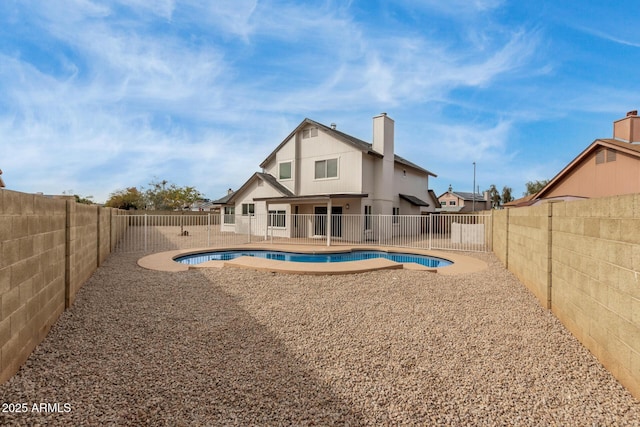 rear view of property with a patio area, a fenced backyard, a fenced in pool, and a chimney