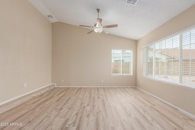 empty room featuring visible vents, a textured ceiling, light wood-type flooring, and lofted ceiling