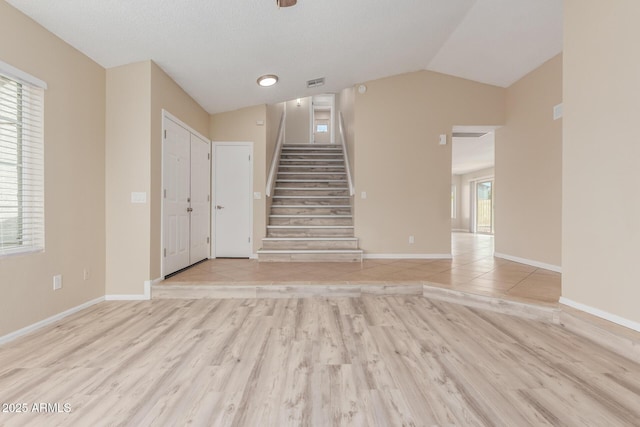 interior space with baseboards, lofted ceiling, visible vents, and wood finished floors