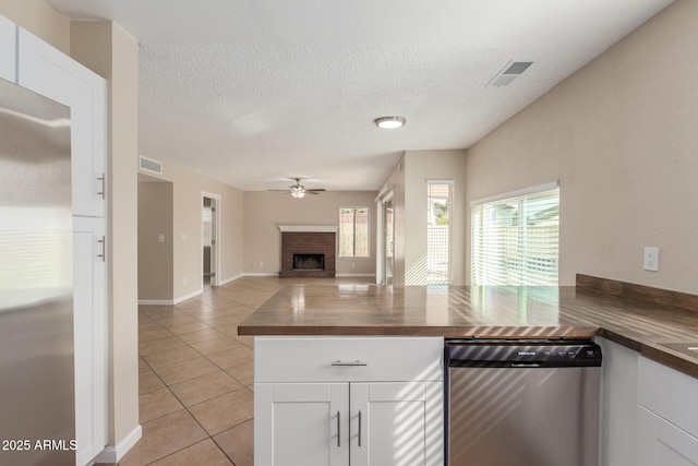 kitchen featuring visible vents, wooden counters, light tile patterned flooring, a fireplace, and appliances with stainless steel finishes