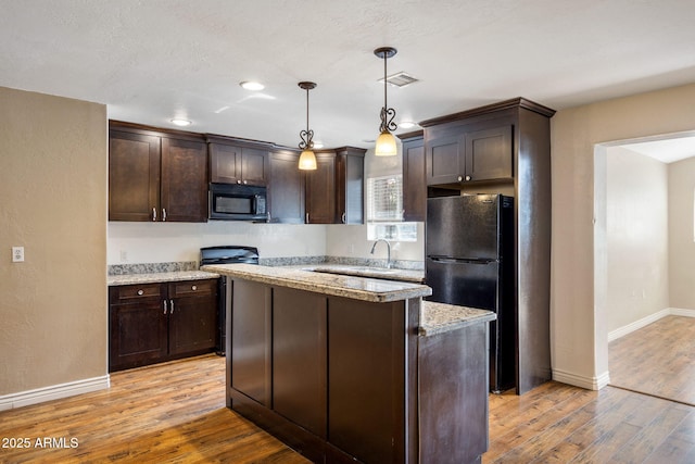 kitchen with pendant lighting, light stone counters, dark brown cabinetry, and black appliances