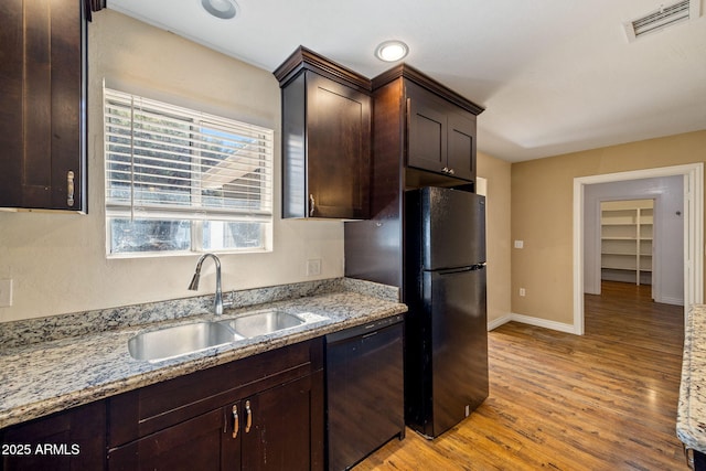 kitchen featuring light stone countertops, sink, dark brown cabinetry, and black appliances