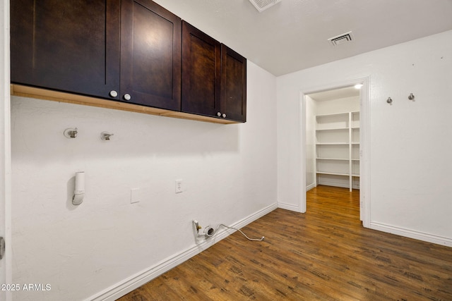 laundry area with gas dryer hookup, cabinets, and dark wood-type flooring