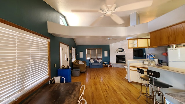 kitchen with a fireplace, lofted ceiling, white fridge, ceiling fan, and light wood-type flooring