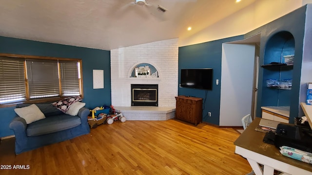 living room featuring lofted ceiling, a brick fireplace, and light hardwood / wood-style flooring