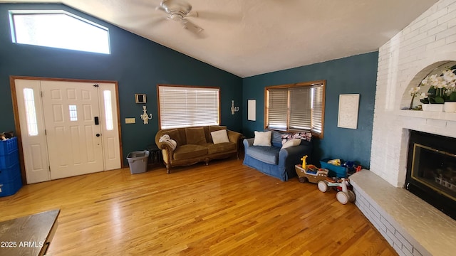 living room featuring ceiling fan, lofted ceiling, a fireplace, and light hardwood / wood-style floors