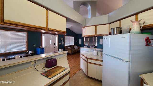 kitchen featuring white refrigerator, lofted ceiling, and white cabinets