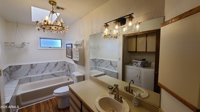 bathroom with a washtub, independent washer and dryer, a chandelier, vanity, and toilet