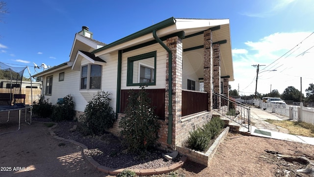 view of side of home with a porch and a trampoline