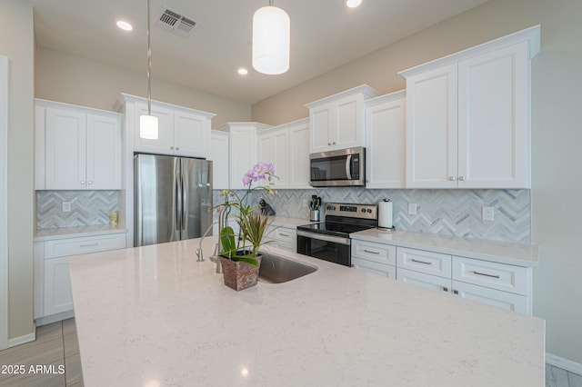 281 E Shamrock Dr, Chandler, AZ 85286 - kitchen with stainless steel appliances, an island with sink, tasteful backsplash, white cabinets, and recessed lighting