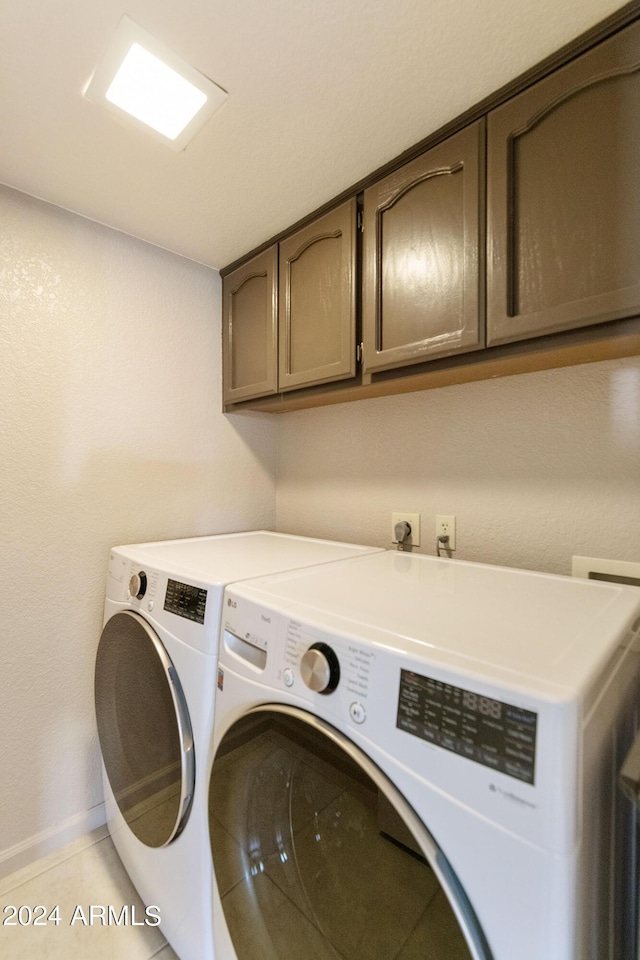 laundry area featuring cabinets, light tile patterned floors, and washing machine and clothes dryer