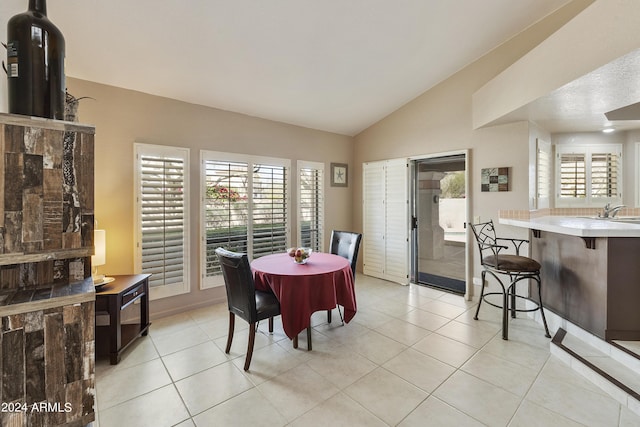 tiled dining room featuring sink and lofted ceiling