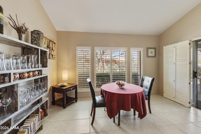 dining space with light tile patterned flooring and lofted ceiling