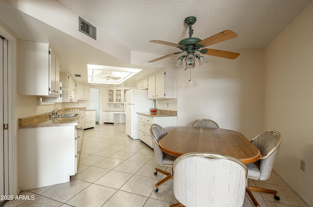 dining area with light tile patterned floors, a ceiling fan, visible vents, and a textured ceiling