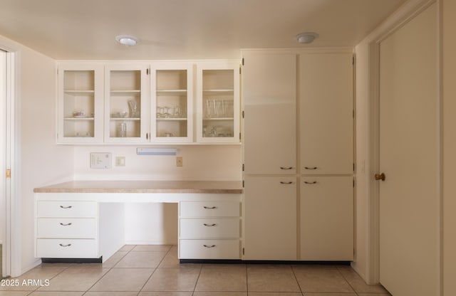 kitchen featuring glass insert cabinets, light countertops, built in study area, and light tile patterned flooring