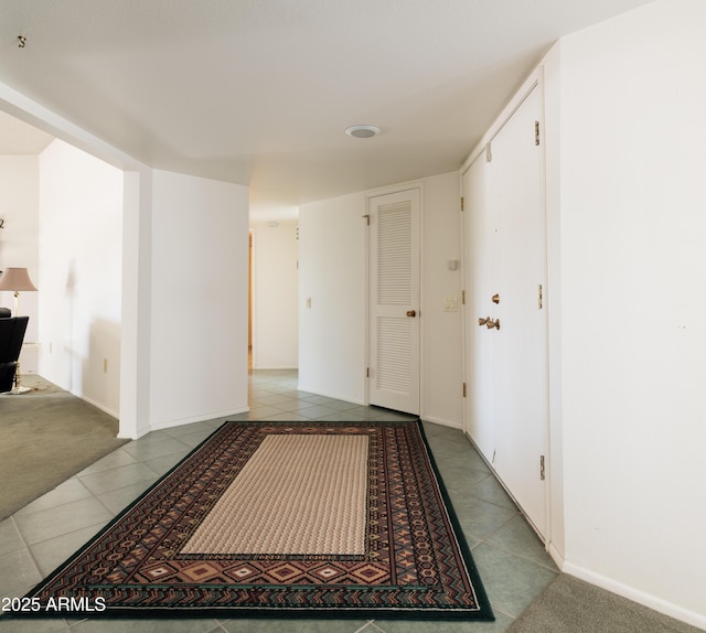 corridor with carpet, tile patterned flooring, and baseboards