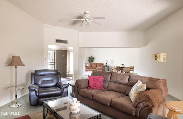 living room with carpet, visible vents, ceiling fan, and a textured ceiling