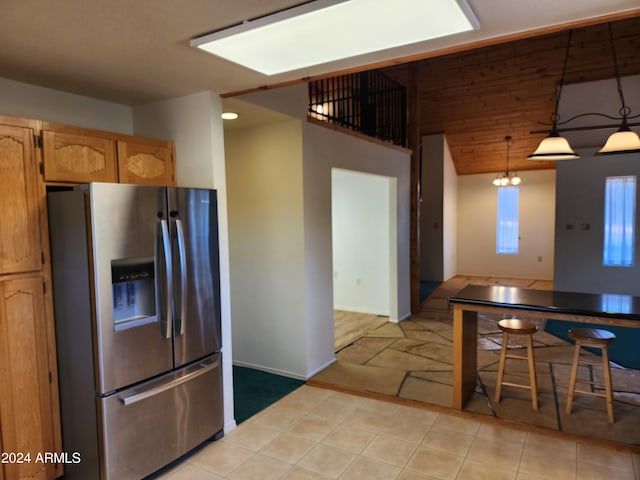 kitchen with stainless steel fridge with ice dispenser, light tile patterned floors, hanging light fixtures, and light brown cabinetry