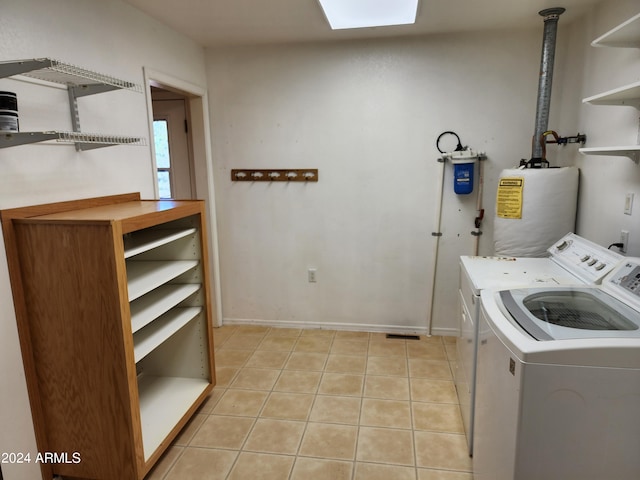 clothes washing area featuring water heater, washer and clothes dryer, and light tile patterned flooring