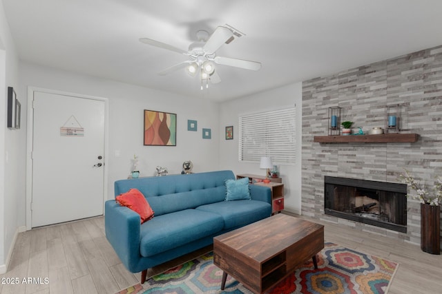 living room with ceiling fan, light hardwood / wood-style flooring, and a tiled fireplace