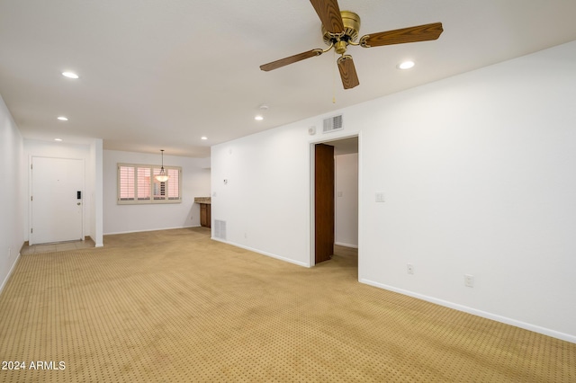 unfurnished living room featuring light colored carpet and ceiling fan