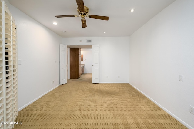 unfurnished bedroom with connected bathroom, light colored carpet, and ceiling fan