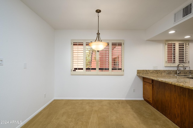 unfurnished dining area featuring sink and light carpet