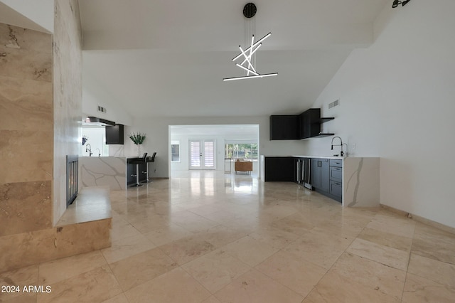 unfurnished living room featuring sink and high vaulted ceiling