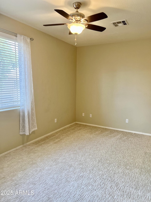 carpeted empty room featuring visible vents, baseboards, and a ceiling fan