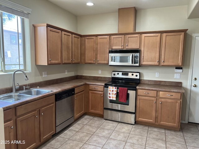 kitchen featuring a sink, dark countertops, a wealth of natural light, and stainless steel appliances