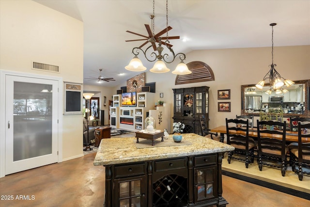 kitchen featuring concrete floors, ceiling fan with notable chandelier, stainless steel microwave, visible vents, and pendant lighting
