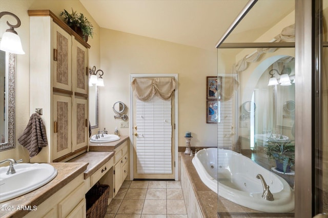 full bath with tile patterned floors, vaulted ceiling, a tub with jets, and a sink