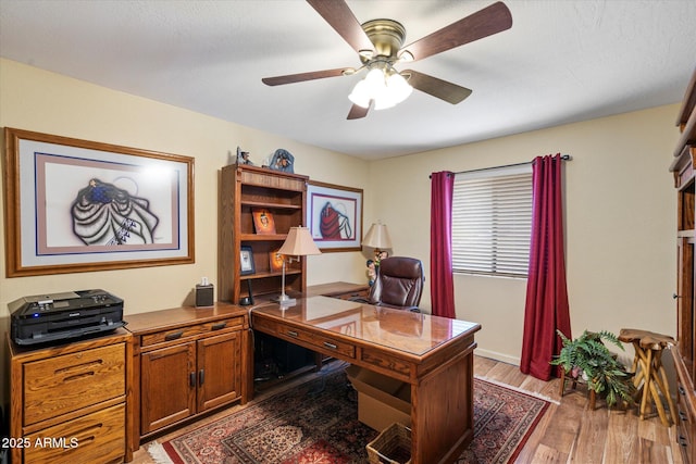 office with light wood-style floors and a ceiling fan
