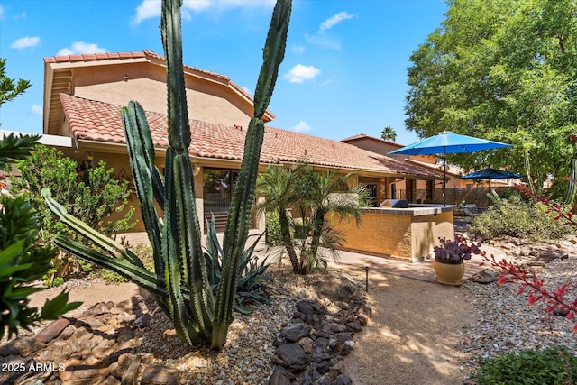 rear view of house featuring fence, exterior kitchen, a tile roof, stucco siding, and a patio area