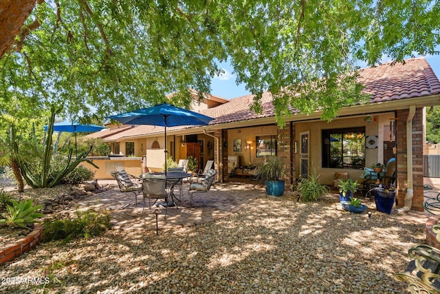 rear view of house featuring a patio, exterior kitchen, and a tiled roof