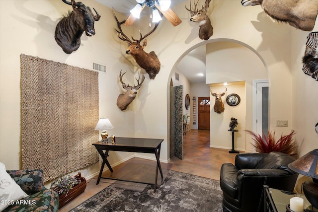 living room featuring arched walkways, ceiling fan, visible vents, and concrete floors