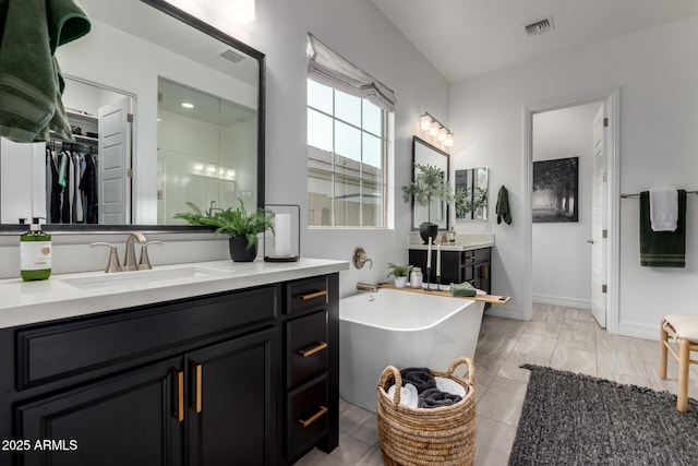 1931 E Aster Pl, Chandler, AZ 85286 - bathroom featuring two vanities, a freestanding bath, a shower stall, and a walk in closet