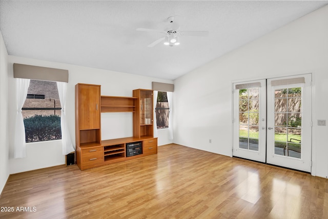 unfurnished living room with vaulted ceiling, plenty of natural light, light wood-type flooring, and french doors