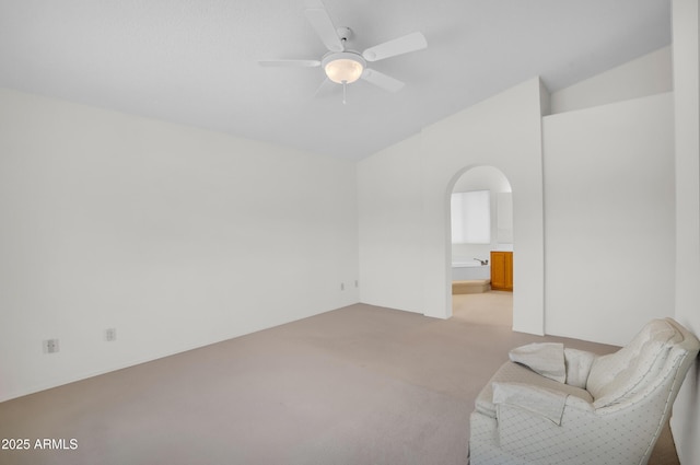 unfurnished room with light colored carpet, lofted ceiling, arched walkways, and a ceiling fan