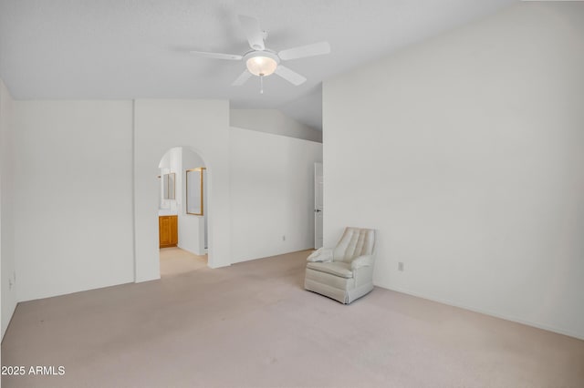unfurnished room featuring light carpet, ceiling fan, arched walkways, and vaulted ceiling