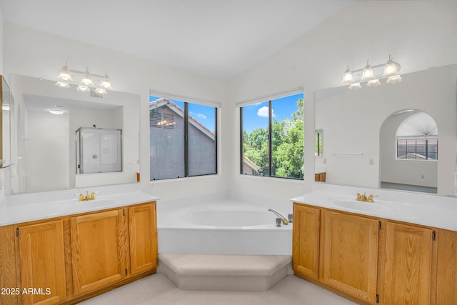 full bathroom with a shower stall, two vanities, a garden tub, and lofted ceiling