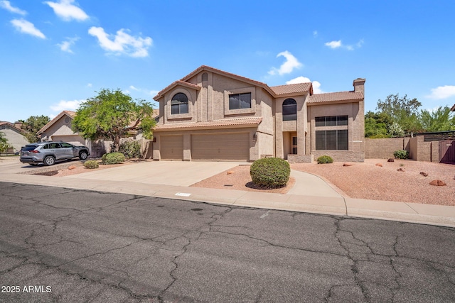 mediterranean / spanish house with stucco siding, a tile roof, an attached garage, a chimney, and concrete driveway