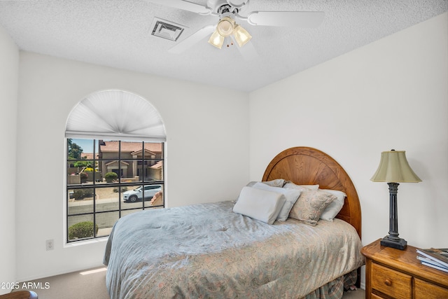 carpeted bedroom featuring a ceiling fan and a textured ceiling