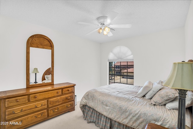 bedroom featuring light colored carpet, a ceiling fan, and a textured ceiling