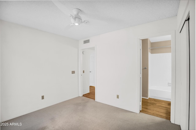 unfurnished bedroom featuring carpet floors, a closet, a textured ceiling, and a ceiling fan