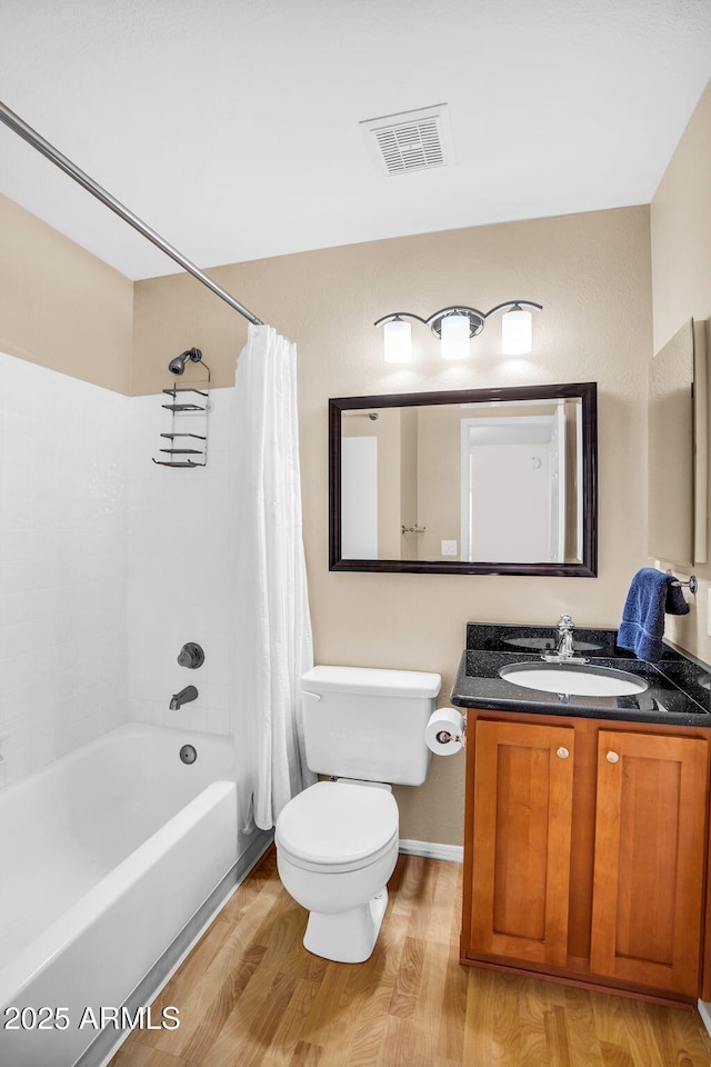 full bathroom with wood finished floors, shower / bathtub combination with curtain, toilet, and vanity