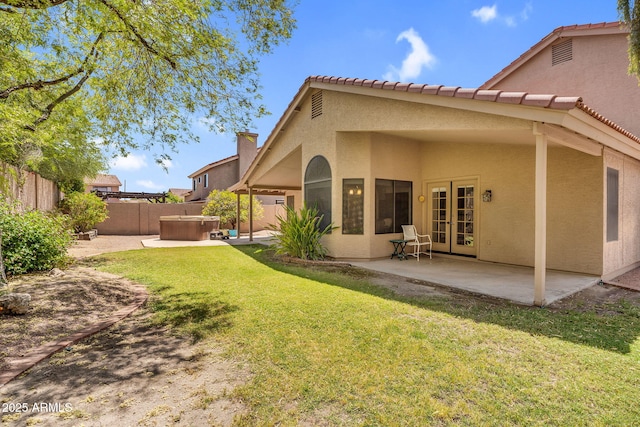 back of property featuring a hot tub, a patio, stucco siding, french doors, and a chimney