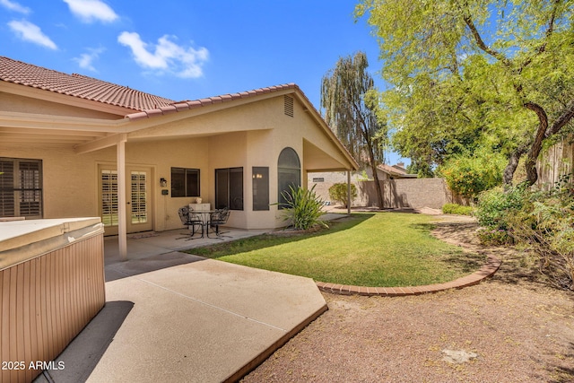back of property with a patio area, stucco siding, a hot tub, and a tiled roof
