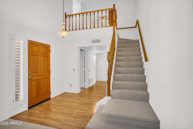 entrance foyer featuring stairway, wood finished floors, and a high ceiling
