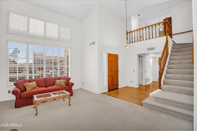 carpeted living room featuring a high ceiling and stairs